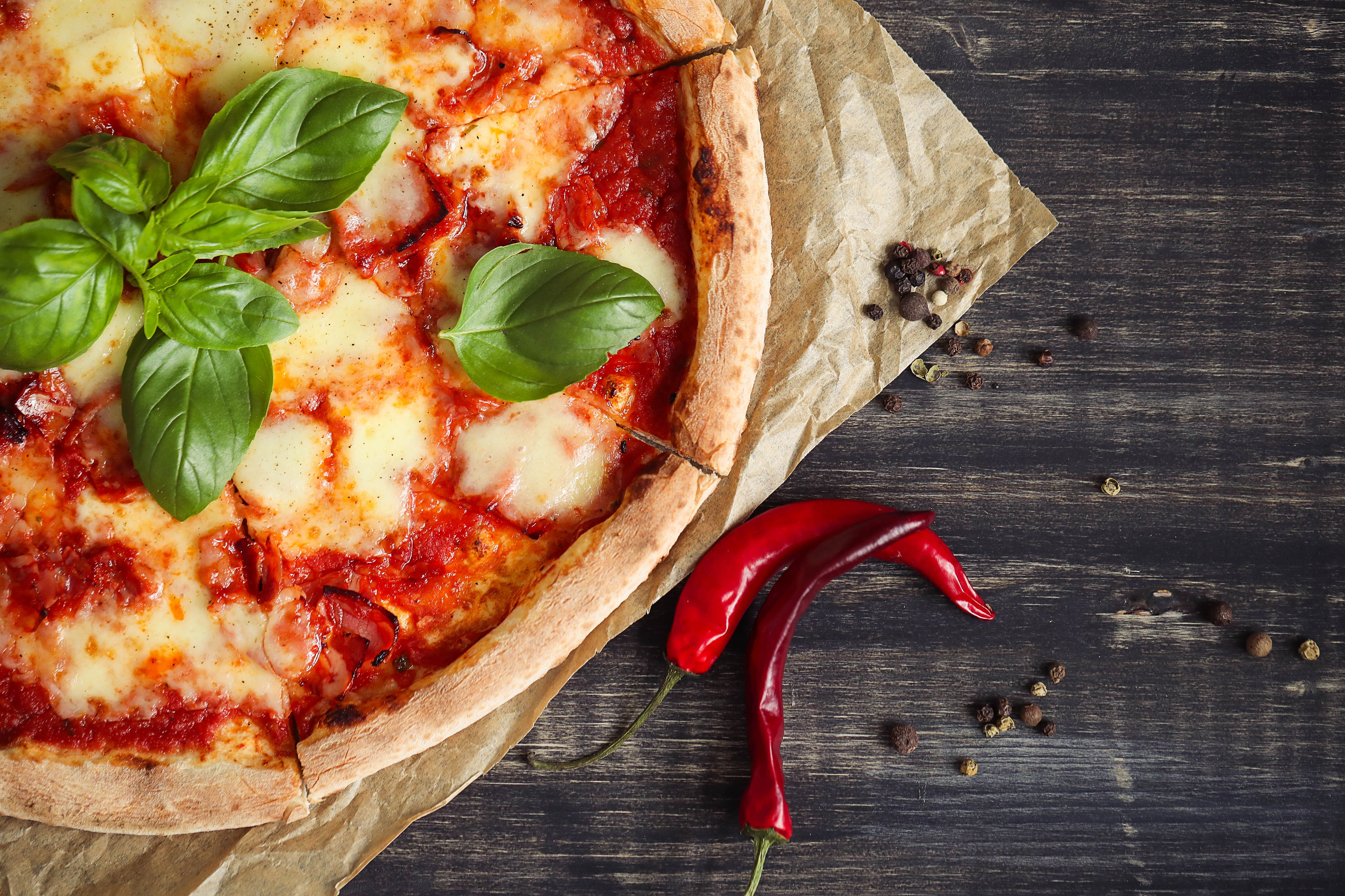 Freshly baked pizza with red chilies and basil.